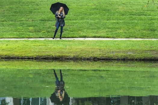 A gorgeous blonde model poses outdoors in her fall clothes while walking in a park