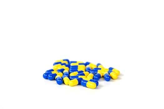 Closeup group of yellow and blue capsule medicine on white background.