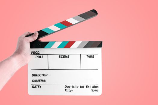 Hand of a man holding a cinema film slate isolated on pastel color background.