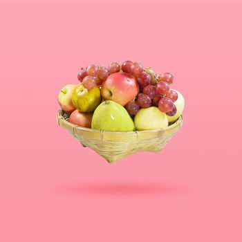 Group of many fruits in a bamboo basket isolated on beautiful pink color pastel background, with clipping path.