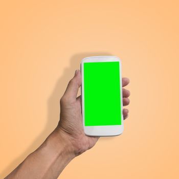 Hand holding smart-phone with green screen isolated on beautiful pastel color background, with clipping path.