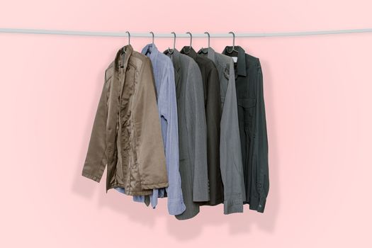 Men's suits and jackets hung on clothes hangers isolated on pink pastel color background, with clipping path.