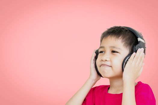 Asian boy wearing a red shirt and wear wireless headphones to listen to music and smiling happily isolated on beautiful pastel color background.