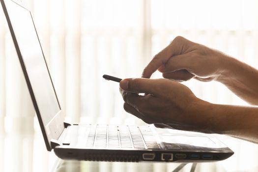 Closeup hands of businessmen are using smartphones and laptops in the office.