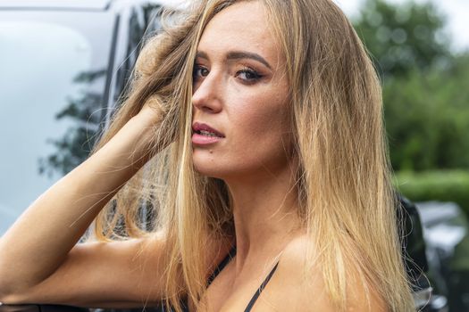 A gorgeous blonde model poses with a black truck on a fall day