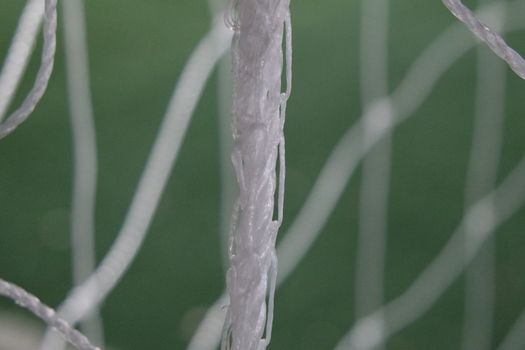 Night view of a soccer goal net under flood lights. Closeup view of goal net in a soccer playground