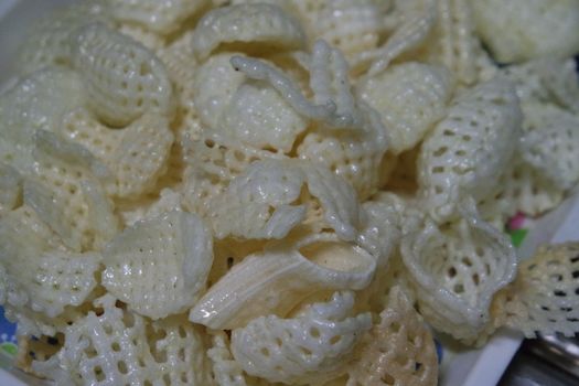Closeup view of freshly fried chips as fast food for tea break. Potato chips with spices sprinkled on it. Fast food background for advertisements.