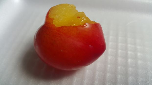 Closeup view of red plum on a white grey background. Freshly harvested plum making heart shape appearance in the view from angle.