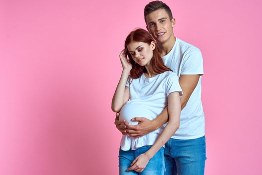 pregnant mom and happy father on pink background Young family waiting for baby. High quality photo