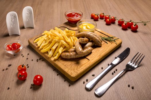 Grilled sausages with french fries with ketchup sauce and mustard on a wooden stand.