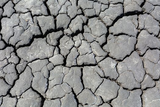 Drought, dried cracked earth. Cracks in the clay. Water shortage problem. The heat of distress is hunger. Background texture corrosion of the earth Gray color