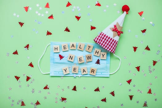 inscription from wooden blocks of a healthy new year on a medical protective mask and on a new year background