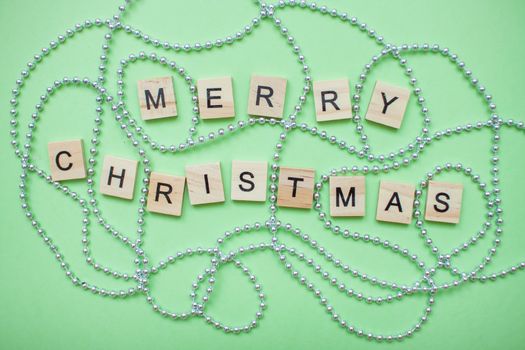 inscription merry christmas in a new year frame of silver beads on a green background