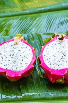 Ripe dragon fruit on a wet green leaf. Vitamins, fruits, healthy foods.