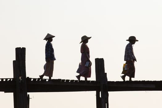 Silhouettes of local women in hats walking on u bien bridge Mandalay, Myanmar. High quality photo