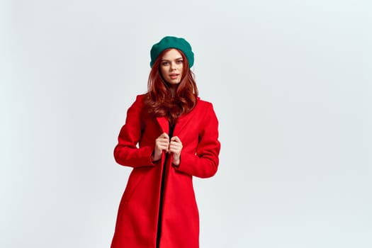 Portrait of a woman in a red coat and in a green hat dark clothes light background model cropped view. High quality photo