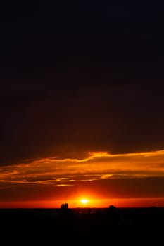 Heavy cloudy sky at sunset. Orange line of light between black clouds. A landscape of beautiful nature.