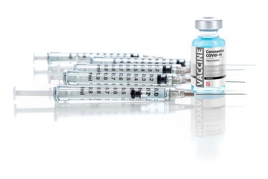 Coronavirus COVID-19 Vaccine Vial and Several Syringes On Reflective Surface.