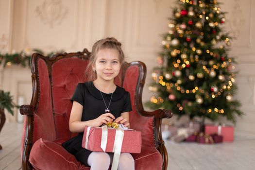 A little girl opens a Christmas present from Santa. Christmas tale. Happy childhood.