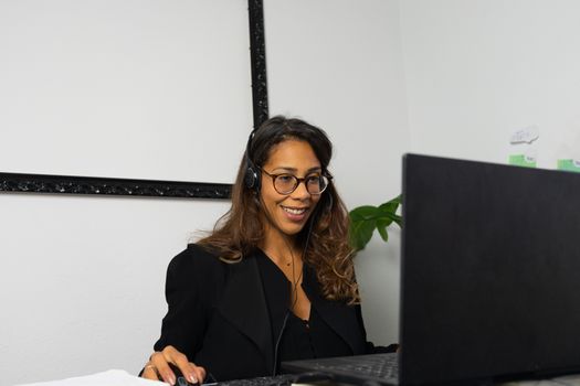 Portrait of beautiful young afro american woman working from home online with headphones