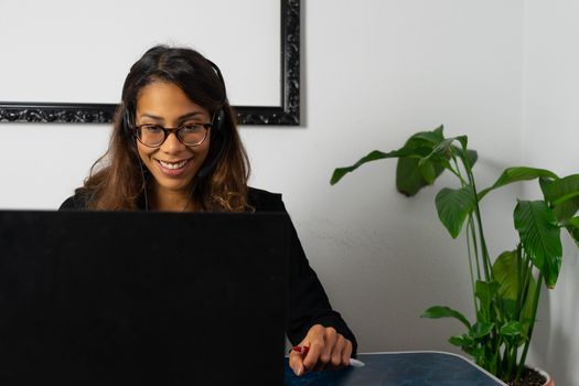 Portrait of beautiful young afro american woman working from home online with headphones