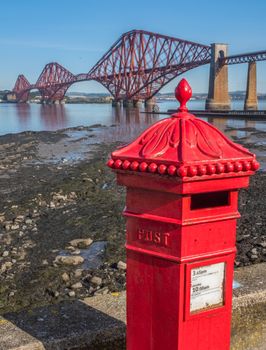 A Bright Red Vintage British Post Box In Front Of The Iconic Forth Rail Bridge In Edinburgh