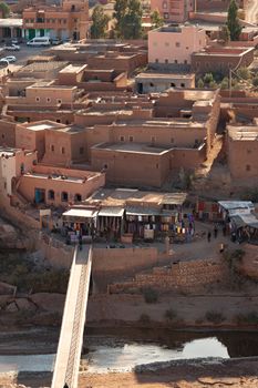 The new town seen from Ait Ben Haddou ksar Morocco, ancient fortress that is a Unesco Heritage site. Beautiful late afternoon light with honey, gold coloured mud brick construction the kasbah, or fortified town dates from 11th cent. and is on the former caravan route from the Sahara and Marrakech. The location has been used for many famous movies. High quality photo