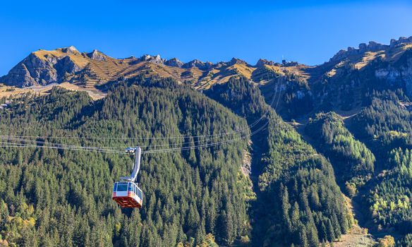 Cable car running towards Mannlichen (Maennlichen) from Wengen, famous tourist destination in Swiss Alps on Bernese Oberland, on a sunny autumn day, Switzerland