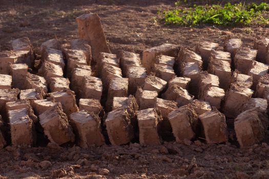 Traditional mud or clay bricks drying in the sun at Ait Ben Haddou ksar Morocco, ancient fortress that is a Unesco Heritage site. Beautiful late afternoon light with honey, gold coloured mud brick construction the kasbah, or fortified town dates from 11th cent. and is on the former caravan route from the Sahara and Marrakech. The location has been used for many famous movies. High quality photo