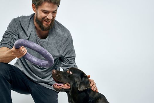 Man with dog training gray ring doing exercises pets light background. High quality photo