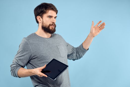 Man holding tablet in hands wireless technology internet lifestyle studio blue background emotions. High quality photo