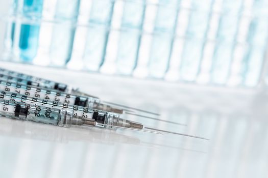 Abstract of Scientific Needle Syringes and Test Tubes Containing Blue Chemical In Rack.