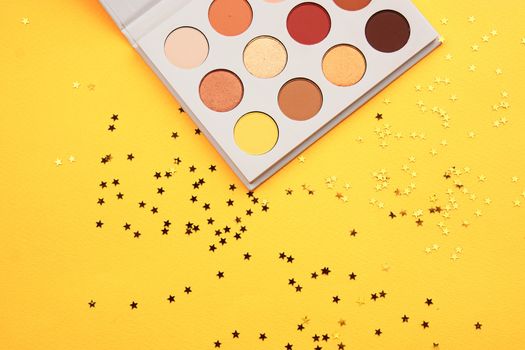 Eyeshadow palette on a yellow background and different colors of cosmetics. High quality photo