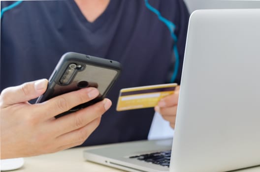 Man Shopping Online Using Laptop With Credit Card.Hands holding credit card and smartphone.