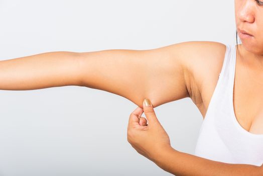 Close up of Asian woman pulling excess fat on her under arm, problem armpit skin, studio isolated on white background, Healthy overweight excess body concept