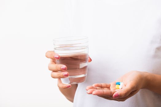 Closeup young Asian woman hold pill drugs in hand ready take medicines with a glass of water, studio shot isolated on white background, Healthcare and medical pharmacy concept