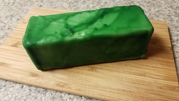 cheese encased or sealed in green wax on wood cutting board