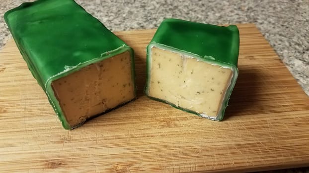 cut cheese encased or sealed in green wax on wood cutting board