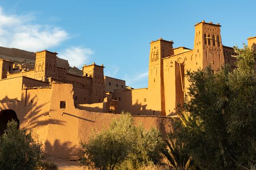 Looking up towards the citadel of Ait Ben Haddou ksar Morocco, ancient fortress that is a Unesco Heritage site. Beautiful late afternoon light with honey, gold coloured mud brick construction the kasbah, or fortified town dates from 11th cent. and is on the former caravan route from the Sahara and Marrakech. The location has been used for many famous movies. High quality photo