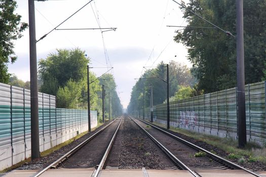 Railway tracks with noise protection walls and trees in the background