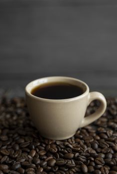 Cup of coffee with roasted coffee beans background. Mug of black coffee