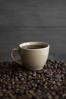 Cup of coffee with roasted coffee beans background. Mug of black coffee