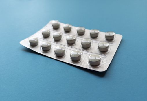 A blister of tablets on blue background. Medical concept. Stock photography.