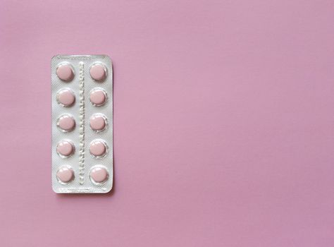 A blister of soft pink pills on pink background. Monochrome simple flat lay with pastel texture with copy space. Medical concept. Stock photography.