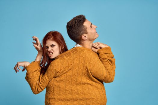 couple in yellow sweater posing against blue background cropped view. High quality photo