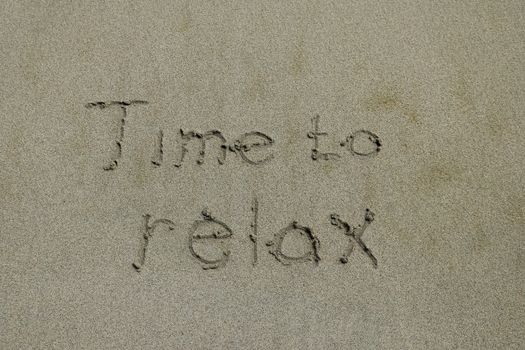 time to relax, concept written on sandy beach.
