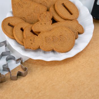 Young woman is decorating Christmas Gingerbread House cookies biscuit at home with frosting topping in icing bag, close up, lifestyle.