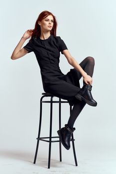 woman high chair indoors full length black dress red hair model boots. High quality photo