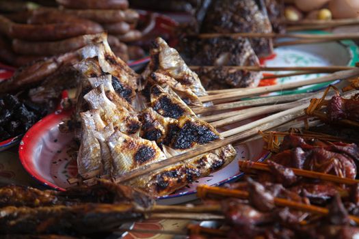 Laos, street food. Traditional food cooked at road sides in stalls on skewers for grilling, chicken, fish, birds High quality photo