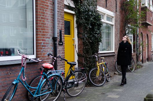 Photograph of a Spanish blonde girl dressed in black walking through the winter streets of a Dutch town full of bikes.
